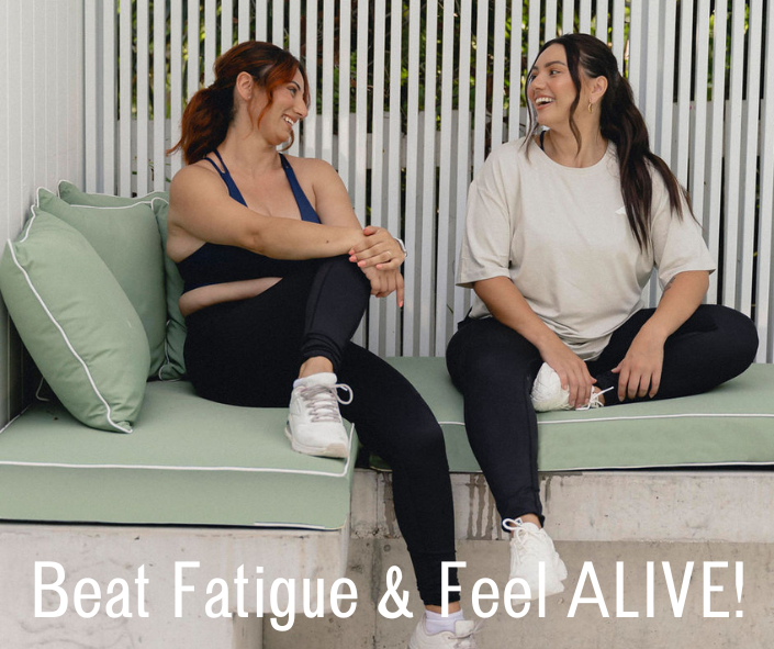 Two women sitting on a couch, sharing a moment of laughter, with the message "Beat Fatigue & Feel ALIVE!" encouraging rest and rejuvenation.