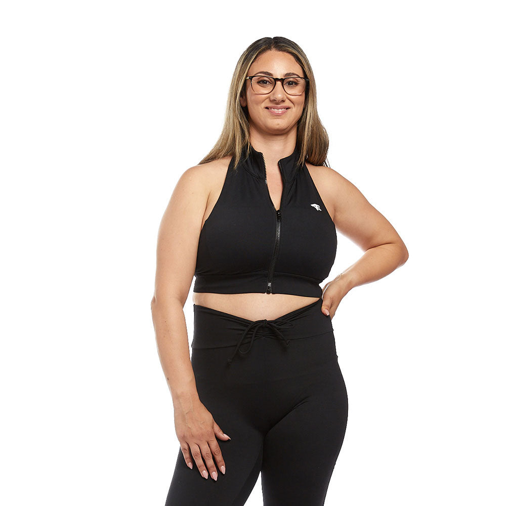 A woman standing confidently in a black Active Elite halter top, looking empowered while highlighting the top's form-fitting and supportive style.