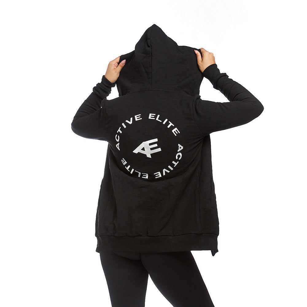 A back view of a woman wearing a black Active Elite zip-up hoodie with the brand's logo displayed in large print on the back. The hoodie’s hood is up, and the design creates a sleek, sporty look.