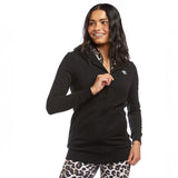 A woman wearing a black Active Elite zip-up hoodie, paired with leopard print leggings. She poses confidently, holding onto the zipper, adding a dynamic, energetic flair to the outfit.